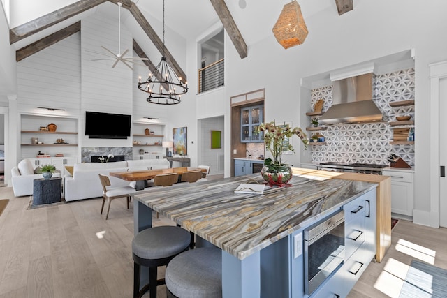 553 Old Compass Rd, Daniel Island, SC 29492 - kitchen featuring wall chimney exhaust hood, stainless steel microwave, high vaulted ceiling, beam ceiling, and light wood-type flooring