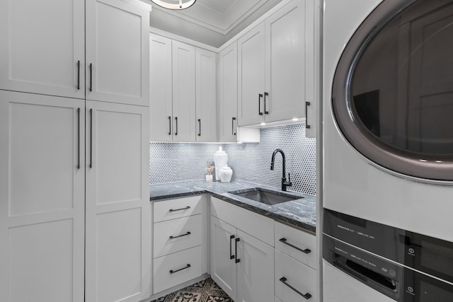 553 Old Compass Rd, Daniel Island, SC 29492 - kitchen with a sink, stacked washing machine and dryer, dark stone counters, and white cabinetry