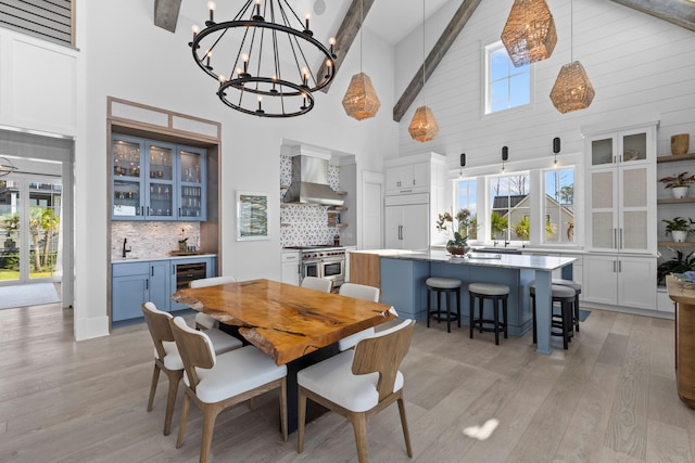 553 Old Compass Rd, Daniel Island, SC 29492 - dining space featuring high vaulted ceiling, light wood-style floors, wine cooler, a chandelier, and plenty of natural light