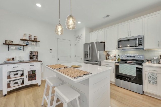 432 Eva St, Moncks Corner, SC 29461 - kitchen with light wood-type flooring, tasteful backsplash, stainless steel appliances, a center island, and white cabinetry
