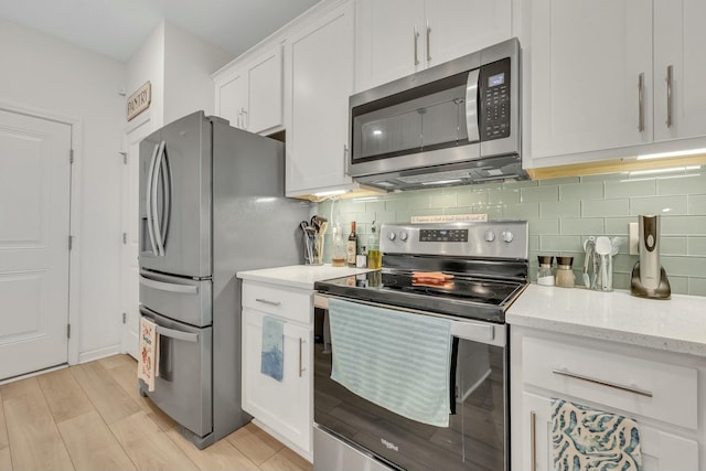 432 Eva St, Moncks Corner, SC 29461 - kitchen with light stone countertops, tasteful backsplash, appliances with stainless steel finishes, white cabinets, and light wood-type flooring