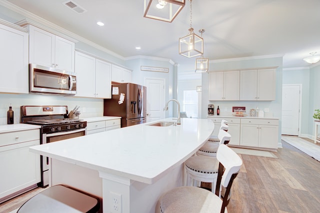 kitchen featuring sink, stainless steel appliances, an island with sink, light hardwood / wood-style floors, and white cabinets