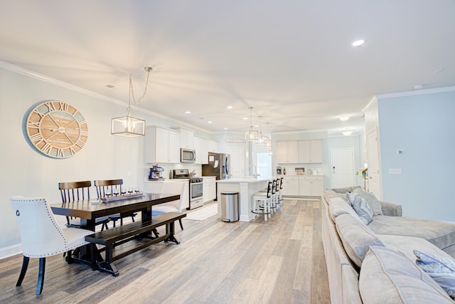 dining area with light wood-type flooring, ornamental molding, and sink