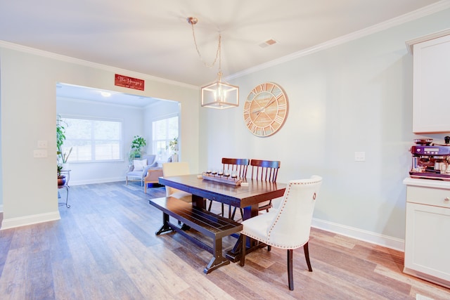 dining room featuring light wood-type flooring, crown molding, and a chandelier