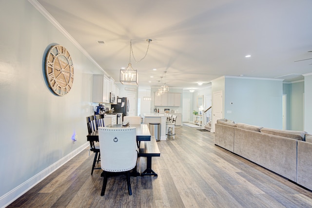 dining space featuring crown molding, an inviting chandelier, and light wood-type flooring