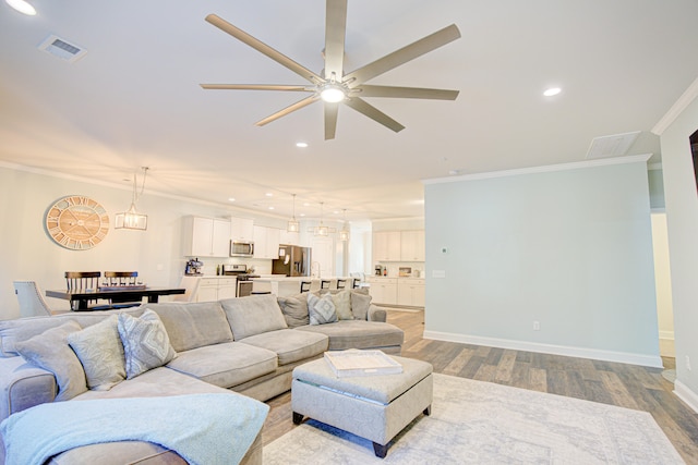 living room featuring ceiling fan, ornamental molding, and light hardwood / wood-style flooring