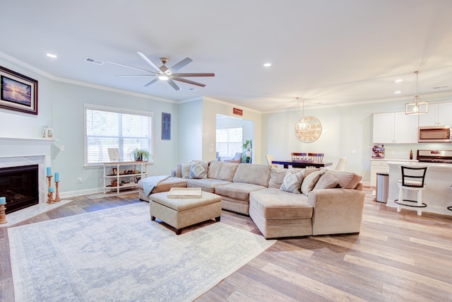 living room with light hardwood / wood-style flooring, ceiling fan, and crown molding