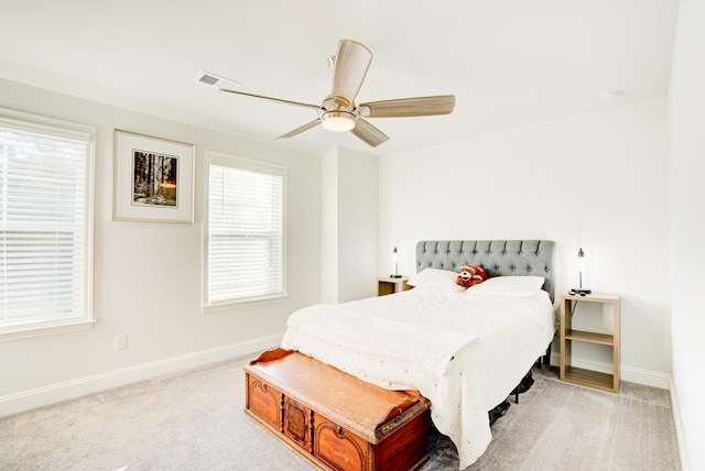 carpeted bedroom featuring multiple windows and ceiling fan