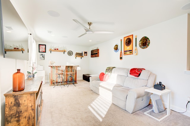 living room featuring light carpet, indoor bar, and ceiling fan