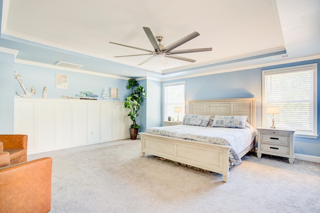 bedroom featuring a raised ceiling, ceiling fan, crown molding, and light carpet