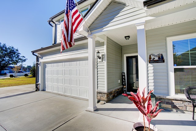 view of exterior entry with a garage and covered porch