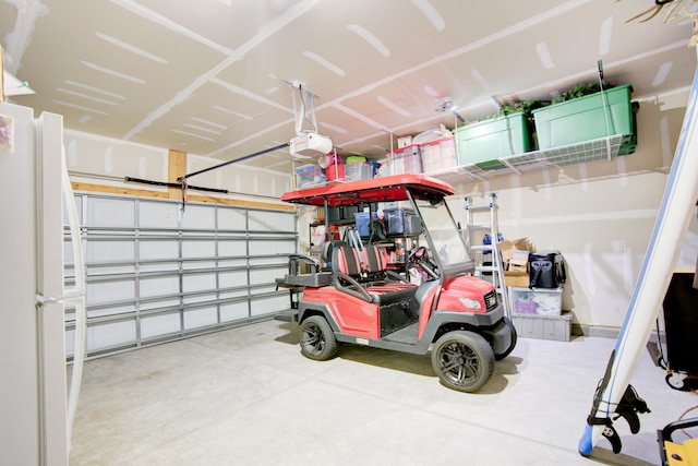 garage featuring white fridge and a garage door opener