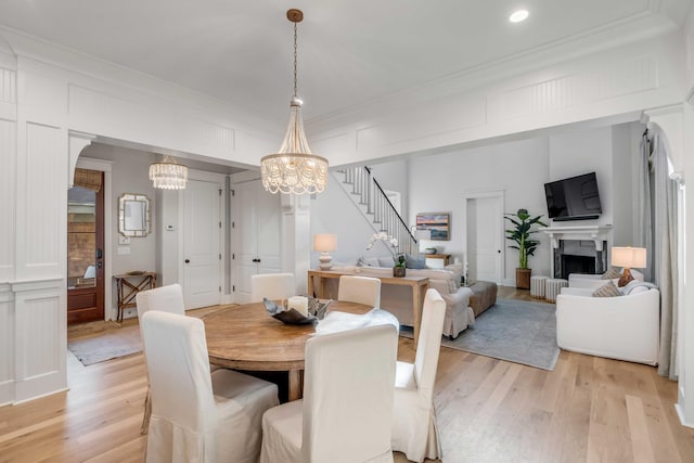 dining area with ornamental molding, an inviting chandelier, and light hardwood / wood-style flooring