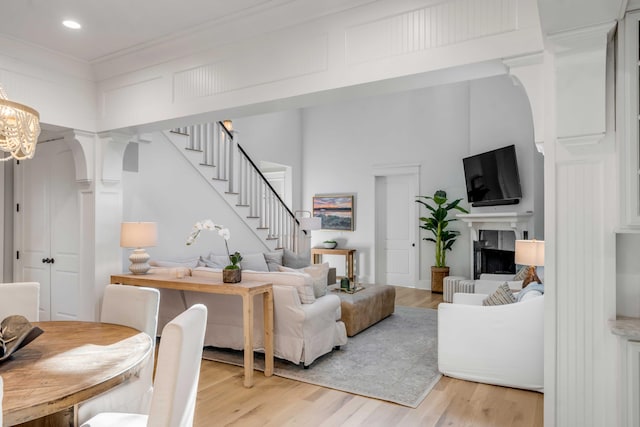 living room featuring an inviting chandelier, crown molding, and light hardwood / wood-style floors