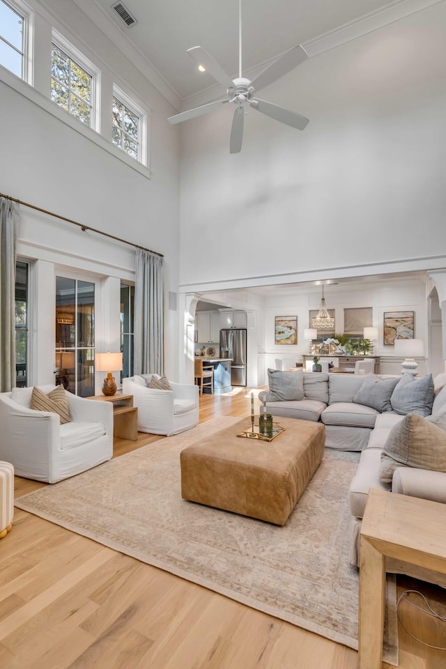 living room with a high ceiling, ornamental molding, and wood-type flooring