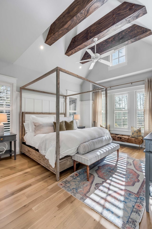 bedroom featuring ceiling fan, light wood-type flooring, and vaulted ceiling with beams