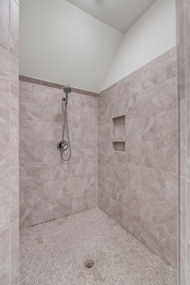 bathroom featuring lofted ceiling and tiled shower