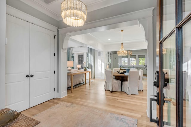 dining space with crown molding, a chandelier, and light wood-type flooring