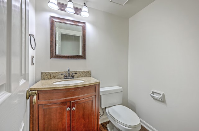 bathroom with toilet, vanity, and baseboards