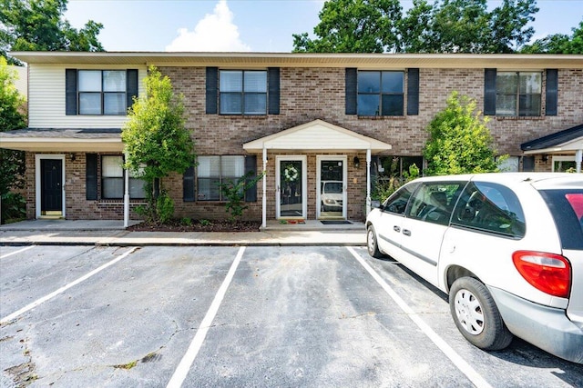 townhome / multi-family property with uncovered parking and brick siding