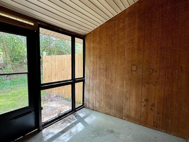 empty room with a wealth of natural light and wood walls