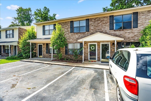 view of property featuring brick siding and uncovered parking