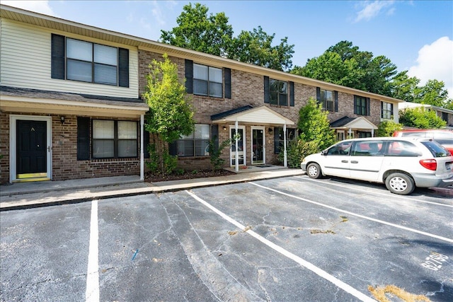 exterior space with brick siding and uncovered parking