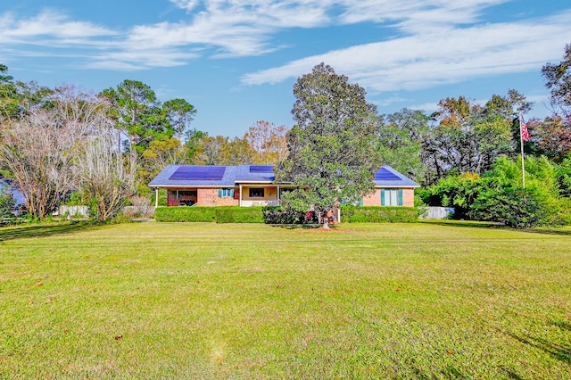 single story home featuring solar panels and a front lawn