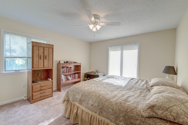 bedroom with ceiling fan, light carpet, and a textured ceiling