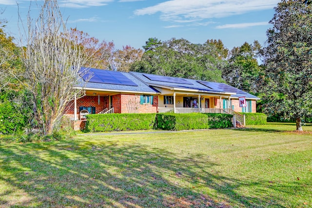 ranch-style home with covered porch, solar panels, and a front yard