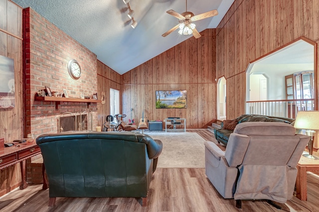 living room with high vaulted ceiling, track lighting, ceiling fan, light wood-type flooring, and a textured ceiling