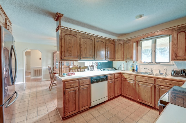 kitchen with dishwasher, sink, kitchen peninsula, stainless steel fridge, and a textured ceiling