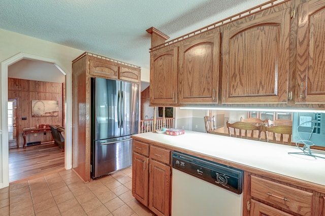 kitchen with a textured ceiling, white dishwasher, stainless steel refrigerator, and light tile patterned flooring