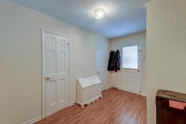 doorway to outside with light hardwood / wood-style floors and a textured ceiling