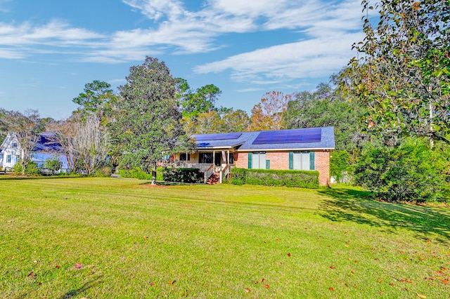 single story home with a front yard and solar panels