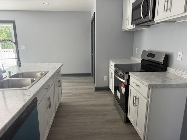 109 NW Haddock Rd, Orangeburg, SC 29115 - kitchen with appliances with stainless steel finishes, a sink, wood finished floors, light countertops, and white cabinets