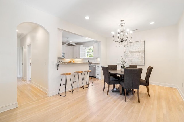 dining room with light wood-type flooring and ceiling fan with notable chandelier