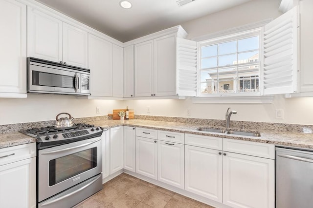 kitchen with light stone counters, sink, white cabinets, and appliances with stainless steel finishes