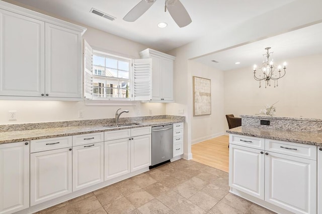 kitchen featuring pendant lighting, stainless steel dishwasher, sink, white cabinetry, and light stone countertops