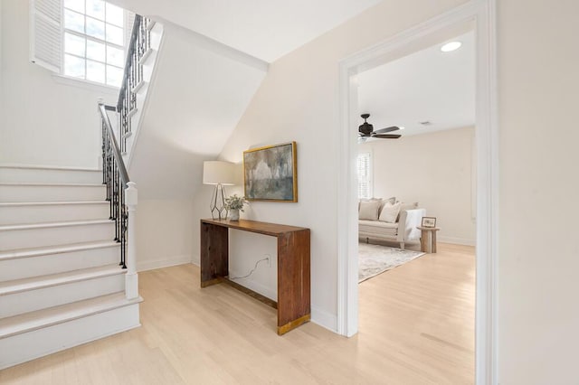 staircase with ceiling fan, a healthy amount of sunlight, wood-type flooring, and vaulted ceiling