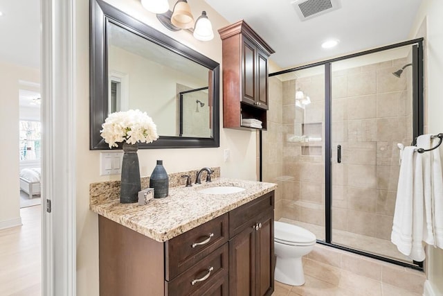 bathroom featuring toilet, tile patterned floors, an enclosed shower, and vanity