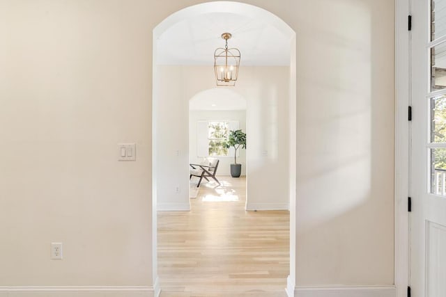 corridor featuring light hardwood / wood-style floors and an inviting chandelier