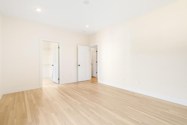 unfurnished bedroom featuring a spacious closet, a closet, and light wood-type flooring