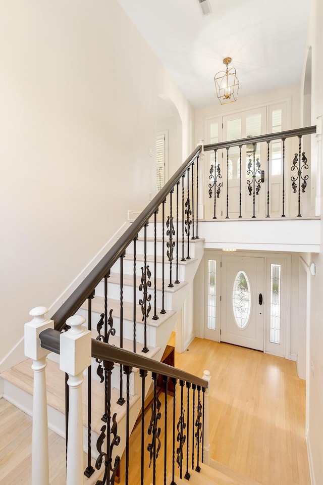 stairway with an inviting chandelier and wood-type flooring