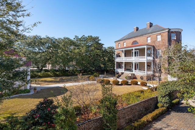 back of property featuring a lawn, a balcony, and covered porch