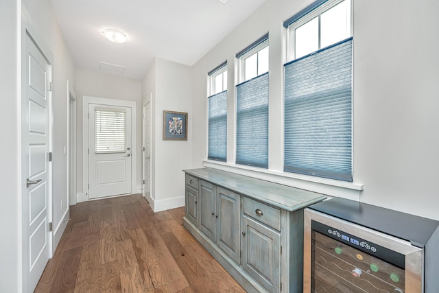 hallway featuring baseboards, dark wood-type flooring, and wine cooler