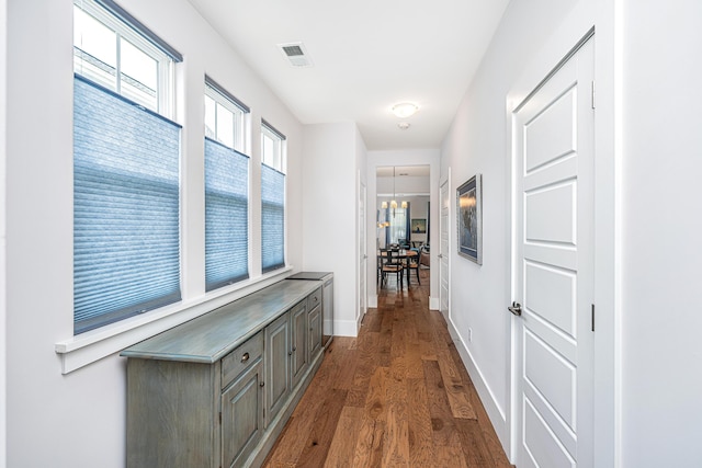corridor featuring baseboards, dark wood-style flooring, and visible vents