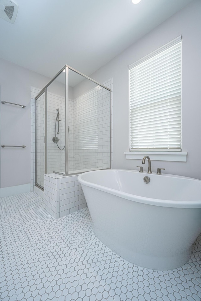 bathroom with tile patterned flooring, a freestanding tub, visible vents, and a shower stall