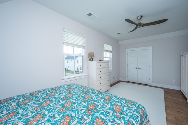 bedroom featuring a ceiling fan, visible vents, wood finished floors, baseboards, and a closet