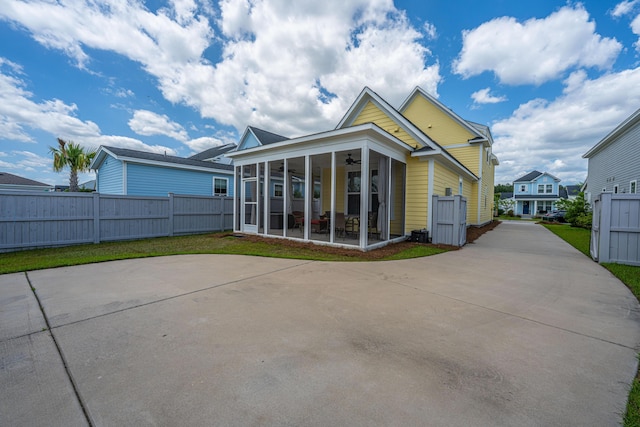 back of property featuring a sunroom, ceiling fan, fence, and concrete driveway